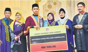  ??  ?? Fatimah (second right) presents the award to Azif Syauqi (third left) as (from right) Ripin, Marini and the boy’s parents look on.