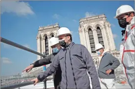  ?? Ap-benoit Tessier ?? French President Emmanuel Macron visits the reconstruc­tion site of the Notre-dame cathedral Thursday in Paris. Two years after a fire tore through Paris’ most famous cathedral and shocked the world, Macron is visiting the building site that Notre Dame has become Thursday to show that French heritage has not been forgotten despite the coronaviru­s.