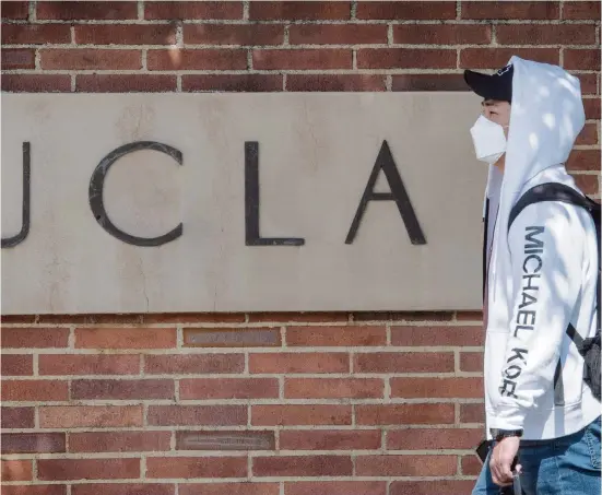  ?? MARK RALSTON TNS ?? A student wears a face mask to protect against COVID-19 as he leaves the campus of UCLA in Westwood, Calif., on March 6.