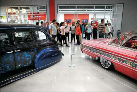 ?? AP/JAE C. HONG ?? Visitors examine a 1939 Chevrolet Master Deluxe named Gangster Squad ’39, (left) and Jesse Valadez’s Gypsy Rose, a customized 1964 Chevrolet Impala, during “The High Art of Riding Low” at the Petersen Automotive Museum in Los Angeles. The exhibition...