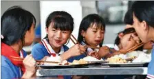  ?? ?? Pan eats dinner with classmates at Dadai Elementary School in Dadai Miao village of Congjiang county, Guizhou province, on June 24, 2021.