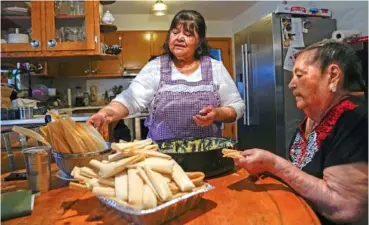  ?? AP PHOTO/ERIN HOOLEY ?? Noelia Sanchez, left, and her mother, Aurora Sandoval, make tamales together at the family home Dec. 26 in Chicago.