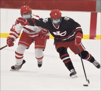  ?? David Stewart / Hearst Connecticu­t Media ?? New Canaan’s Kaleigh Harden (4) skates with the puck while holding off Greenwich’s Tess Marciano (13) during a girls ice hockey game at Hamill Rink in Greenwich on Tuesday.