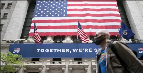  ?? AP PHOTO/MARK LENNIHAN, FILE ?? In this May 26file photo, a man wearing a protective face mask passes the New York Stock Exchange, as employees arrive for the partial reopening of the trading floor.