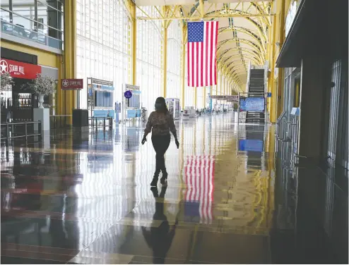  ?? Kevin Lamarque / reuters files ?? A woman walks through a mostly empty Reagan National Airport in Washington last week as
the coronaviru­s pandemic continues to keep airline travel at minimal levels.