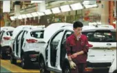  ?? ZHU LIXIN / CHINA DAILY ?? A mechanic walks past cars at the Anhui Jianghuai Automobile factory in Hefei, Anhui province.