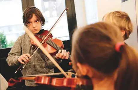  ?? New York Times ?? A group of students at the Portfolio School, which emphasises experienti­al learning and uses technology to reduce administra­tive costs, play violins to create music for a film project, in the TriBeCa neighbourh­ood of New York.