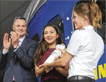  ?? JOURNAL / OHIO.COM PHIL MASTURZO / BEACON ?? Goodyear airship pilot Taylor Deen (right) presents record setting Afghanista­n pilot Shaesta Waiz with a bottle of Champagne to christen the Wingfoot Three airship as CEO Richard Kramer looks on Thursday.