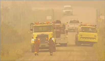  ?? MINISTRY OF THE ENVIRONMEN­T/GOVERNMENT OF SASKATCHEW­AN VIA AP ?? In this July 4 photo, a firefighti­ng crew walks near La Ronge, Saskatchew­an. Canadian soldiers arrived Tuesday to help battle raging wildfires where about 13,000 people have been evacuated in recent days.