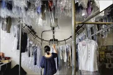  ?? Christina House Los Angeles Times ?? STACY KIM, 62, co-owner of Arroyo Cleaners in Pasadena, sorts through clothes. “We want better for our children,” she said. “We worked many hours, sacrificed almost everything, so they could do better.”