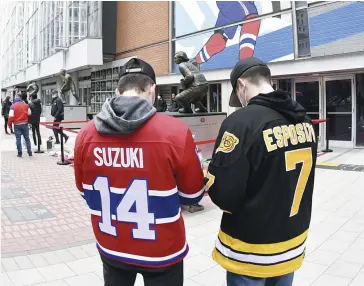  ?? PHOTO USA TODAY SPORTS ?? Ces fans du Canadien et des Bruins oublient l’adversité pour se recueillir quelques instants devant le bronze de Guy Lafleur à l’entrée du Centre Bell.