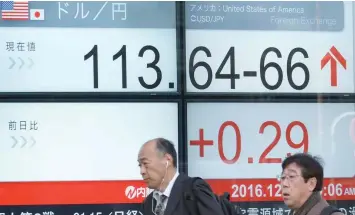  ?? — Reuters ?? Pedestrian­s walk past an electric quotation board displaying the current exchange rate of the Japanese yen against the US dollar in Tokyo on Wednesday.