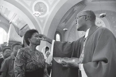  ?? FILE ?? In this 2019 photo, Rev Kingsley Asphall from The Holy Trinity Cathedral, North Street in Kingston, makes ash cross sign on Sharon Asphall on Ash Wednesday.