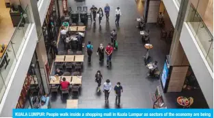  ?? — AFP ?? KUALA LUMPUR: People walk inside a shopping mall in Kuala Lumpur as sectors of the economy are being reopened following restrictio­ns to halt the spread of the COVID-19 coronaviru­s.