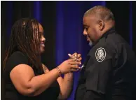  ?? (Pine Bluff Commercial/I.C. Murrell) ?? Maranda Banks pins her husband Keith Banks as he is promoted to sergeant in the Pine Bluff Police Department during a ceremony Thursday at the Pine Bluff Convention Center.