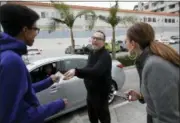  ?? JAE C. HONG — THE ASSOCIATED PRESS ?? Father Jim Sichko, center, gives Nicholas Vadi, left, a $100 bill to congratula­te hime on his birthday while buying lunch for customers at an In-N-Out Burger, in the Hollywood section of Los Angeles.