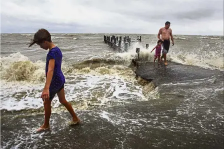  ??  ?? Storm is coming: Residents walking near a pier as Hurricane Harvey approaches the coast in Bacliff, Texas. — AP