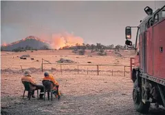  ?? AFP ?? Rural Fire Service volunteer firefighte­rs look on as the New South Wales ‘mega-fire’ approaches Tumbarumba, New South Wales last week.
