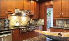  ??  ?? The kitchen features custom cherry cabinetry with custom lighting.