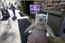  ?? RICH PEDRONCELL­I - THE ASSOCIATED PRESS ?? Truffles, a large stuffed bear, sits outside the Rocky Mountain Chocolate Factory, next to a sign advising customers about social distancing in Lodi, Calif., Wednesday, Dec. 9. Jeanne Bria, the owner of the store, said she relies on foot traffic from nearby restaurant­s.
With a new stay-at-home order that bans in-person dining, Bria said she has seen business drop by 60%.