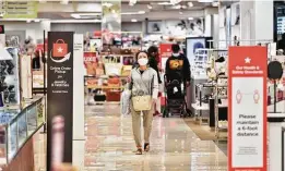  ??  ?? Sporting a protective face mask, a woman walks through the Macy’s store at North Star Mall during early Black Friday shopping.