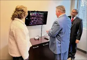  ?? Robert Gavin / Times Union ?? Albany County Executive Daniel Mccoy, accompanie­d by Family Court Judge Richard Rivera and Albany County Department of Children, Youth and Families Moira Manning, plays the video game classic Donkey Kong at the Friday ribbon-cutting of a special room for foster youth in Albany County Family Court.