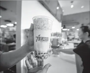  ?? Allen J. Schaben Los Angeles Times ?? A 7 LEAVES employee serves a cup of love cream, containing jasmine milk tea and caramel, in Garden Grove.