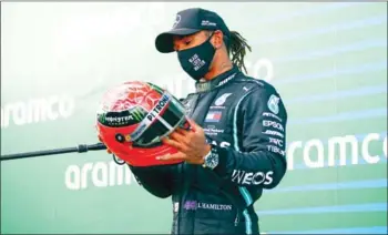 ?? AFP ?? Lewis Hamilton admires Michael Schumacher’s red helmet after tying the Grand Prix win record.