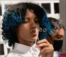  ?? ?? Tenth grader Ishaun Carruth blows bubbles during the vigil for teacher Meghan Marohn at Shaker High School on Friday. Bubbles were passed around at the end of the event.