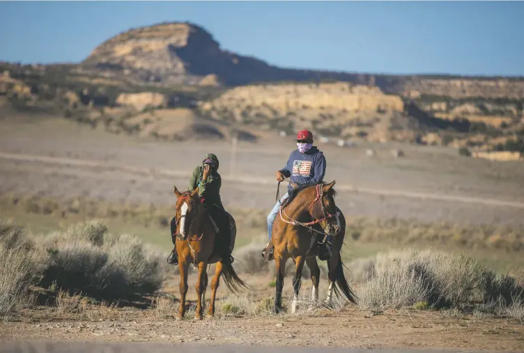  ?? photos Sharon Chischilly ?? Two Navajo Nation residents ride their horses to the nearest food distributi­on center; opposite page, a resident waits at a food distributi­on site;