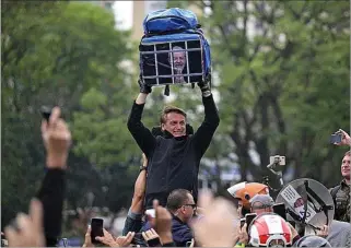  ?? ERNESTO BENAVIDES / AFP ?? El presidente Bolsonaro sostiene una bolsa con la imagen de Lula entre rejas.