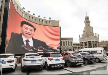  ?? Bloomberg ?? A LARGE screen shows an image of Chinese President Xi Jinping in a vehicle parking area in Xinjiang. Xi has refocused his administra­tion on building up state-owned companies. I