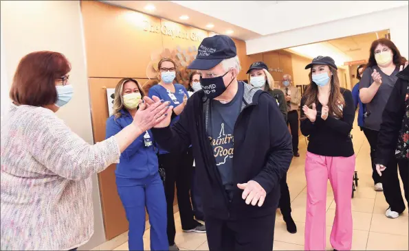  ?? Arnold Gold / Hearst Connecticu­t Media ?? Nurse/case manager Debbie Kaye, left, high-fives George Aiello, of Bethel, Friday as he leaves Gaylord Specialty Healthcare in Wallingfor­d after nearly nine months in hospitals recovering from COVID-19. Aiello has been hospitalze­d since March with COVID-19 and its effects.