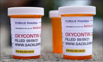  ?? SETH WENIG, FILE — THE ASSOCIATED PRESS ?? Fake pill bottles with messages about Oxycontin maker Purdue Pharma are displayed during a protest outside the courthouse where the bankruptcy of the company is taking place in White Plains, N.Y., on Aug. 9, 2021. A judge said he is extending legal protection­s for members of the Sackler family, on March 2who own Oxycontin maker Purdue Pharma by another three weeks to buy time to work out a new settlement to thousands of lawsuits over the opioid crisis.