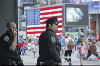 ?? EDUARDO MUNOZ ALVAREZ / GETTY IMAGES ?? New York police officers keep an eye on tourists as they stand guard at Times Square on July 4. Security was heightened after authoritie­s issued an alert calling for vigilance following calls for violence by Islamic State militants.
