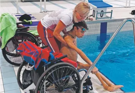  ??  ?? Coach Olesya Alexandrov­a helps Russian paralympic swimmer Alexander Makaro after a training session in Ruza on Thursday. Makarov had been preparing for the Games that his team is now banned from. Vasily Maximov, AFP/Getty Images