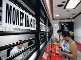  ?? ELOISA LOPEZ • REUTERS ?? Customers receive money from families working abroad at a money remittance centre in Makati City, Metro Manila, Philippine­s.