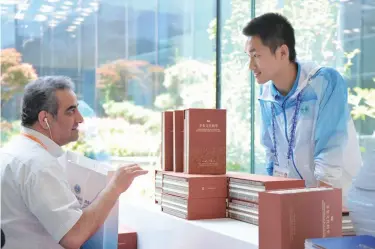  ??  ?? An Iranian journalist inquires from a volunteer about the book series 18th Shanghai Cooperatio­n Organizati­on Summit at the media center of the