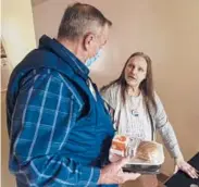  ?? DAVID GOLDMAN/AP 2020 ?? Meals on Wheels of Rhode Island driver Jim Stotler, left, delivers a meal to 66-year-old Rhonda Valoir at her apartment in Pawtucket.