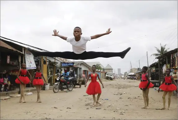  ?? SUNDAY ALAMBA — THE ASSOCIATED PRESS ?? Ballet student Anthony Mmesoma Madu, center, dances in the street as fellow dancers look on in Lagos, Nigeria in August of 2020. Cellphone video showing the 11-year-old dancing barefoot in the rain went viral on social media.