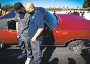  ??  ?? Isaac Llamas (right) stands with his friend Jose Guadarrama, who was driving the 1998 Lincoln Town Car that belonged to his dad, who died of COVID-19 recently.