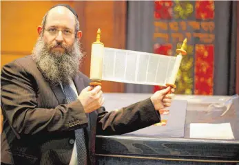  ?? FOTO: ALEXANDER KAYA ?? Rabbiner Shneur Trebnik, hier mit einer kleinen Tora-Rolle, wird am Sonntag die neue Tora-Rolle in die Ulmer Synagoge am Weinhof einbringen.