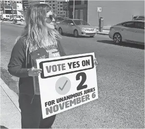  ?? KEVIN MCGILL/AP ?? New Orleans resident Molly Ezell holds a sign promoting a Louisiana constituti­onal amendment that would require unanimous 12-member jury verdicts in serious felony cases in the state.