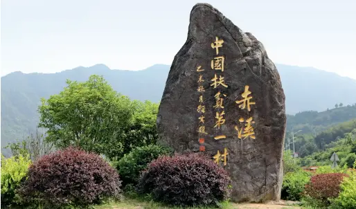  ??  ?? Une stèle a été érigée à l’entrée du village de Chixi avec l’inscriptio­n « le premier village de la lutte contre la pauvreté en Chine ».