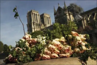  ?? FRANCISCO SECO — THE ASSOCIATED PRESS ?? A bunch of flowers lies by the Seine riverside Thursday near the Notre Dame cathedral, background, in Paris. France is paying a daylong tribute Thursday to the Paris firefighte­rs who saved the internatio­nally revered Notre Dame Cathedral from collapse and rescued its treasures from encroachin­g flames.