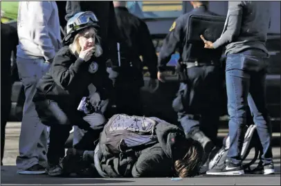  ?? The Associated Press ?? DEADLY FIRE: A unidentifi­ed man falls to the ground after speaking to authoritie­s outside of a warehouse destroyed by a fire Saturday in Oakland, Calif. A deadly fire broke out during a rave at a converted warehouse in the San Francisco Bay Area.