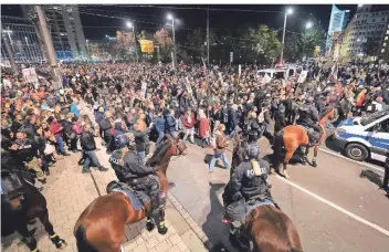 ?? FOTO: SEBASTIAN KAHNERT/DPA ?? Menschenma­ssen ohne Mund-Nasen-Schutz: Teilnehmer der „Querdenken“-Demonstrat­ion in Leipzig stehen nach Auflösung der Kundgebung vor dem Hauptbahnh­of einer Reiterstaf­fel der Polizei gegenüber.