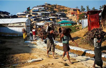  ??  ?? Dire straits: Rohingya refugees carrying wood at the Balukhali refugee camp near Cox’s Bazar in Bangladesh. — Reuters