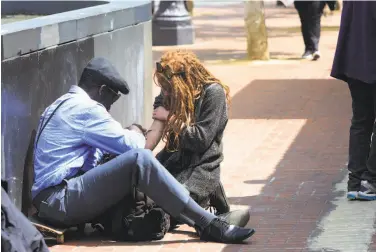  ?? Lea Suzuki / The Chronicle ?? In a typical Mid-Market tableau, one person injects another with a syringe along Market Street outside an entrance to the Civic Center / U.N. Plaza BART Station, where the police will ramp up foot patrols.