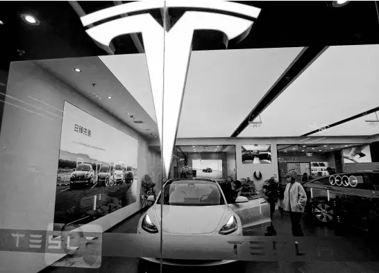  ?? REUTERS ?? Visitors check a Tesla Model 3 car next to a Model Y displayed at a showroom of the U.S. electric vehicle maker on Feb. 4, 2023, in Beijing, China.